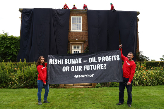 Picture taken and released by environmental action group Greenpeace on August 3, 2023 shows Greenpeace activists on the roof of Britain’s Prime Minister Rishi Sunak’s manor house in Kirby Sigston, northern England, to protest at his backing for new oil and gas licences in the North Sea. [AFP/YONHAP]