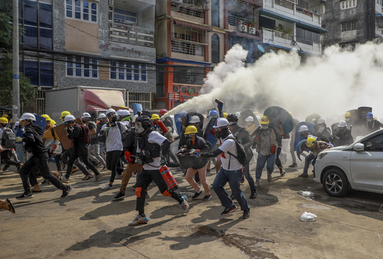 Anti-coup protesters run as one of them discharges a fire extinguisher to counter the impact of tear gas fired by riot policemen in Yangon, Myanmar, March 3, 2021. [AP/YONHAP]