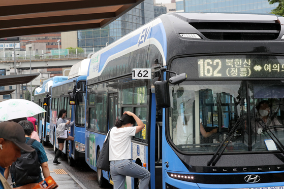 Bus fares will rise at least 300 won ($0.22) starting this Saturday. This file photo dated July 13 shows passengers getting on buses near Seoul Station. [NEWS1]