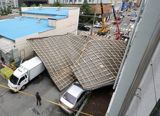 The roof of a structure is seen collapsed onto parked vehicles. [YONHAP]