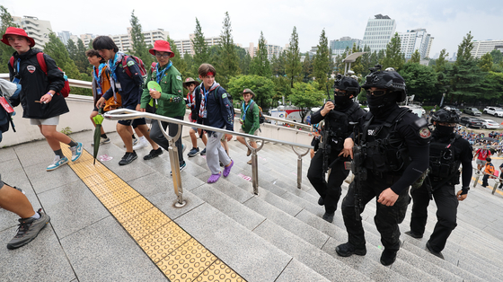 Participants of the 25th World Scout Jamboree enter the Seoul World Cup Stadium in western Seoul on Friday to take part in Friday's ″K-pop Super Live″ concert set to begin at 7 p.m., as military officials patrol the area for a safety inspection. [YONHAP]