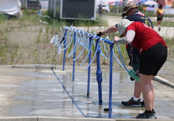 World Scout Jamboree participants try to cool off from the heat on Aug. 2 at the campsite at Saemangeum in Buan County, North Jeolla. Lack of shade and fundamental facilities including showers and toilets were considered a major issue at the beginning of the event. [YONHAP]