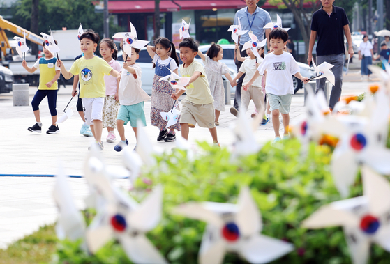 Children from a daycare center in Gwangju run around with paper pinwheels with the Korean national flag on Monday. Korea celebrates the 78th anniversary of its liberation from Japanese colonial rule on Tuesday. [YONHAP]
