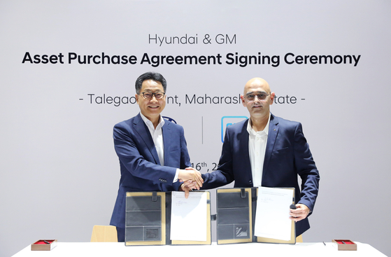Hyundai Motor Executive Vice President Kim Un-soo, left, shakes hands with Asifhusen Khatri, vice president at General Motors, after signing a deal to acquire the U.S. automaker's plant in India on Wednesday. [HYUNDAI MOTOR] 