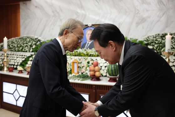 Former President Lee Myung-bak, left, shakes hands with President Yoon Suk Yeol after paying condolences for his late father, Yoon Ki-jung, a professor emeritus of Yonsei University, at Severance Hospital in Seodaemun District, western Seoul, Tuesday. [PRESIDENTIAL OFFICE]