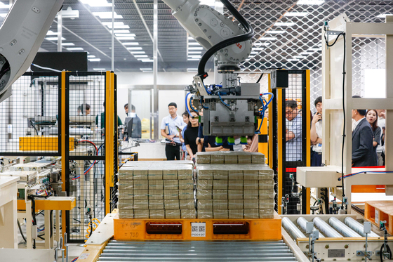 A robot moves bundles of banknotes at the Bank of Korea headquarters in Jung District, central Seoul, on Wednesday. Palletizing robots use robot arms to store and load banknotes on a conveyor belt that distributes the bills to vaults. Pallet lifters will then store the banknotes into a vault and automated guided vehicles inside the vault load them onto the shelves. The process is reversed to release banknotes. [NEWS1]