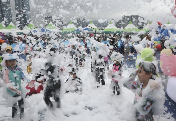 Children and other participants are covered in bubbles during a water festival held in Nam District, Busan on Wednesday. Busan was one of several regions where heat wave warnings were issued that day. The temperature in Busan rose to 31 degrees Celsius (88 degrees Fahrenheit). Seoul rose to 32 degrees Celsius. The weather agency forecasts the heat to continue for the time being, with temperatures rising to 33 degrees Celsius on Thursday. [YONHAP]