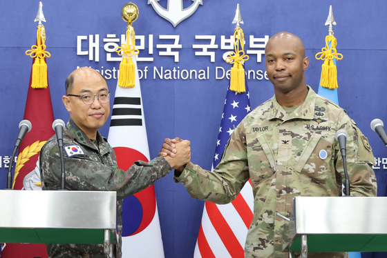 Col. Lee Sung-jun, left, spokesperson for the Joint Chiefs of Staff, joins hands with Col. Isaac Taylor, public affairs director for the U.S. Forces Korea, on Monday at the Ministry of National Defense in Yongsan District, central Seoul, during a joint press briefing announcing the upcoming Ulchi Freedom Shield exercise. [YONHAP]