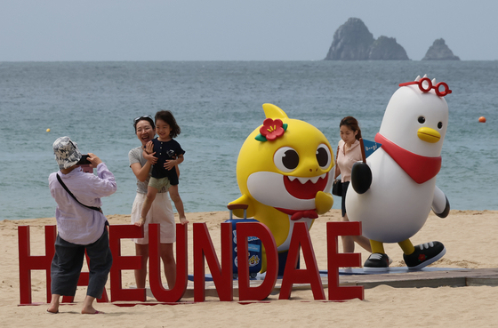 People take photos with Boogi the seagull, Busan's mascot, and Pinkfong Company's Baby Shark, a promotional ambassador for Busan's expo bid, on June 20. [SONG BONG-GEUN]