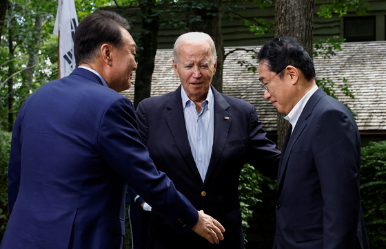 U.S. President Joe Biden, center, greets Korean President Yoon Suk Yeol, left, and Japanese Prime Minister Fumio Kishida, right, during their trilateral summit at Camp David near Thurmont, Maryland, Friday. [REUTERS/YONHAP]