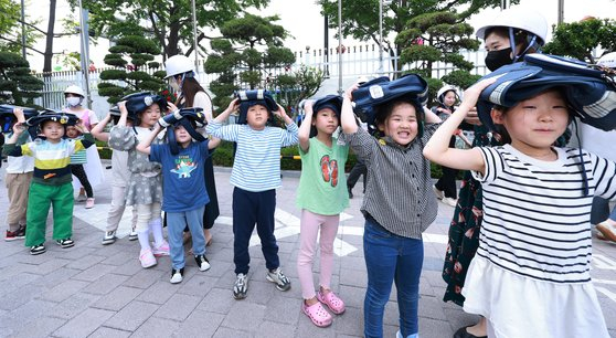 Children hold their school bags over their heads as they take part in a civil evacuation drill at the Central Government Complex in Jongno District, central Seoul, on May 16. [YONHAP]