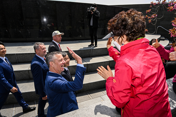 A BIE enquiry mission exchanges a high-five with a Busan citizen during a tour of a United Nations Memorial Cemetery in Korea, the world’s only United Nations cemetery to honor UN military causalities in the Korean War, in April. [YONHAP] 