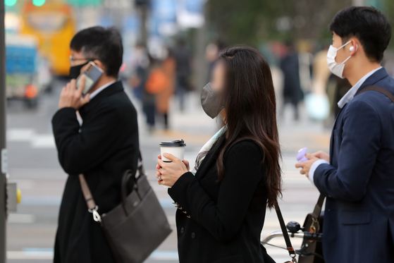 An office worker goes to work with a cup of coffee in hand in Seoul. [NEWS1]