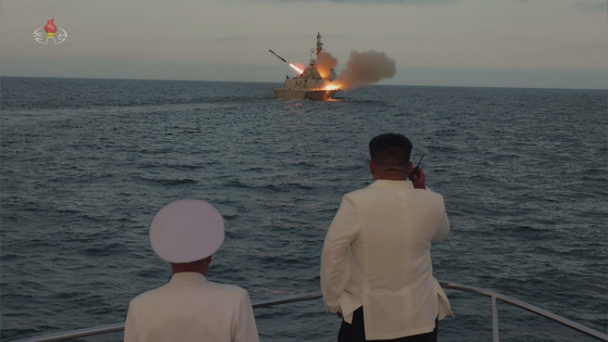 North Korean leader Kim Jong-un, right, observes the launch of a ship-borne cruise missile from a distance in this undated footage released by Pyongyang's state-controlled Korean Central Television on Monday. [YONHAP]