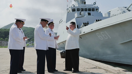 North Korean leader Kim Jong-un, right, gives guidance to naval officials in this footage released by Pyongyang's state-controlled Korean Central Television on Monday. The number of the new naval frigate, 661, can be seen behind him above the dock. [YONHAP]