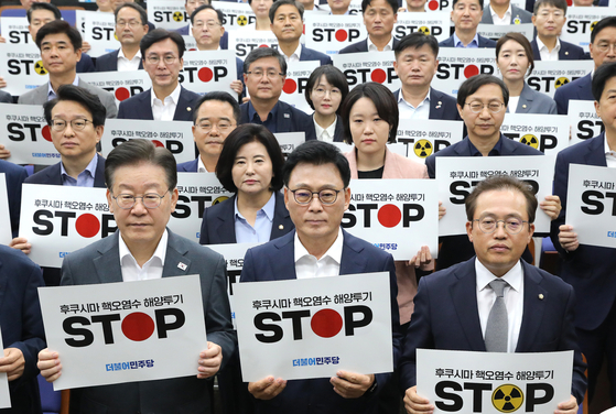 Democratic Party (DP) chief Lee Jae-myung, front left, and DP lawmakers hold a picket sign protesting Japan's discharge of treated radioactive water from the defunct Fukushima nuclear power plant during the party's emergency meeting held at the National Assembly in Yeouido, western Seoul. [NEWS1] 