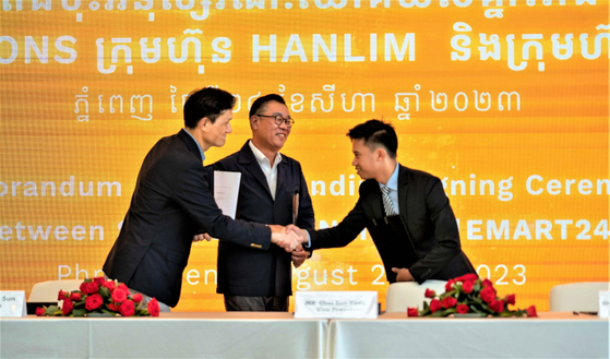 Emart24 Vice President Choi Eun-yong, center, shakes hands with representatives from Cambodia's Saisons Brother Holding and Hanlim Architecture Group during the business agreement ceremony for Emart24's entry into Cambodia on Thursday. [EMART24]
