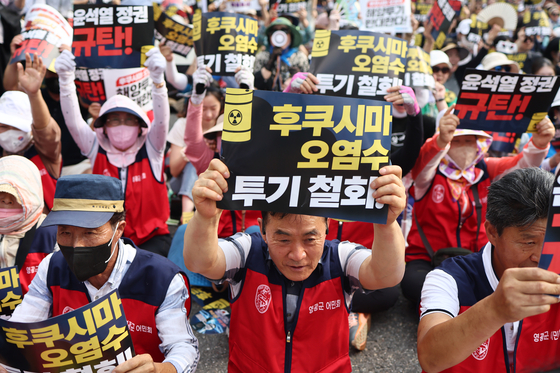 Protestors hold up placards demanding that Japan retract its decision to release radioactive water from the crippled Fukushima nuclear power plant at a rally in Jung District, central Seoul, on Saturday. [YONHAP]