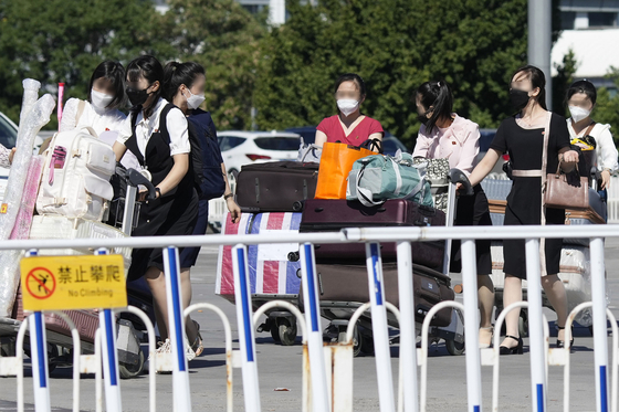 In a photo taken by Kyodo News Agency, North Korean women push trolleys laden with baggage as they walk towards Terminal 2 of Beijing Capital International Airport on Tuesday, the first day that flights by the North's national carrier Air Koryo resumed between Pyongyang and Beijing. [KYODO/YONHAP]