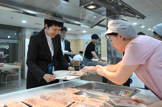 Senior presidential secretary for press affairs Kim Eun-hye, left, is served a tray of sliced raw fish at the in-house cafeteria of the presidential office in Seoul on Monday. [PRESIDENTIAL OFFICE]