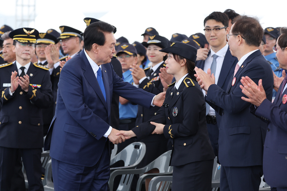 President Yoon Suk Yeol, left, shakes hands with inspector Cho Hyun-jin of the Korea Coast Guard, daughter of the late high-ranking inspector Cho Dong-su, who was honored for his work on policing illegal Chinese fishing boats in the Korean waters off the coast of Incheon in October 2016, at the special commemoration of the 70th anniversary of Day of Korea Coast Guard on Monday in Seo District, Incheon. [YONHAP]