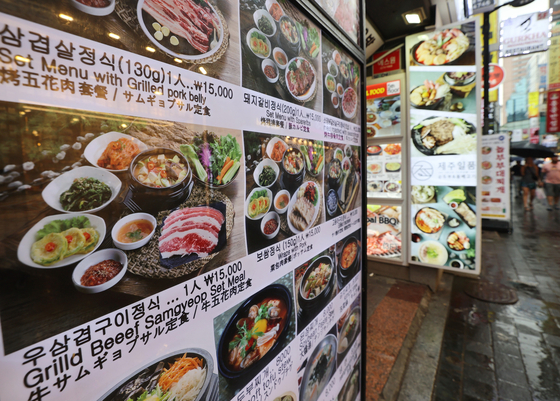 Menu boards displayed in front of a restaurant in Myeong-dong in the Jung District, central Seoul, on Wednesday. The Jung District Office announced that it will require stores in Myeong-dong to display price tags to stamp out overcharging on services and products sold in the area from October. [YONHAP]