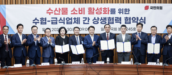 Rep. Sung Il-jong of the People Power Party (PPP) along with the representatives from the National Federation of Fisheries Cooperatives and catering companies take a photo after a agreement ceremony for boosting seafood consumption at the National Assembly on Wednesday. [KIM SEONG-RYONG] 