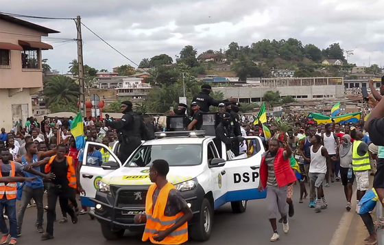 This video grab shows coup supporters cheering police officers in Libreville, Gabon, Wednesday Aug. 30, 2023. Mutinous soldiers speaking on state television announced that they had seized power in and were overturning the results of a presidential election that had seen Gabon President Ali Bongo Ondimba extend his family's 55-year hold on power. [AP/YONHAP]