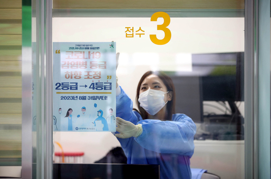 A medical worker posts a notice of Covid-19's impending downgrade from level two to the lowest four on the window of a testing booth at a screening clinic located in Gwangju's Buk District on Wednesday, a day before the classification change takes effect. [GWANGJU BUK DISTRICT OFFICE]