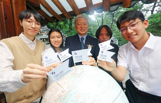 Yeom Jae-ho, president of Taejae University, center, poses for a photo with students of the university's inaugural class at the school's building in Jongno District, central Seoul, on Wednesday. [YONHAP] 