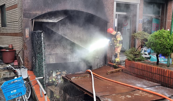 A fire fighter extinguishes the fire that occurred at a bathhouse in Busan on Friday. [YONHAP]