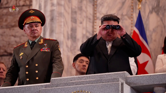 In this footage broadcast by Pyongyang's state-controlled Korean Central Television on July 28, Russian Defense Minister Sergei Shoigu stands next to North Korean leader Kim Jong-un, who is using binoculars to review a military parade held in downtown Pyongyang the previous evening to celebrate the end of active hostilities in the 1950-53 Korean War. [YONHAP]