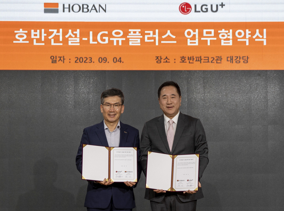 LG UPlus's head of electric vehicle business Hyun Joon-yong, right, and Hoban Construction's Vice President Moon Kap signed a memorandum of understanding on Monday in southern Seoul to build EV chargers inside Hoban Summit apartment complexes. [LG UPLUS]