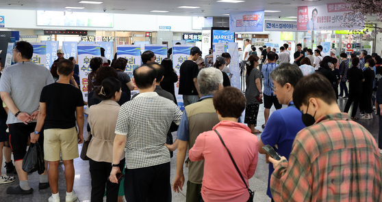 Customers wait in a queue to receive refund vouchers after purchasing seafood products at Noryangjin Fisheries Wholesale Market in Dongjak District, central Seoul, on Sunday. [NEWS1]
