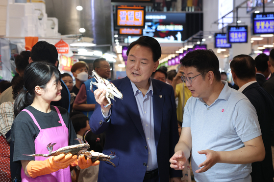 President Yoon Suk Yeol holds up a crab during his visit to Noryangjin Fisheries Wholesale Market in Dongjak District, southern Seoul, on Thursday. [PRESIDENTIAL OFFICE]