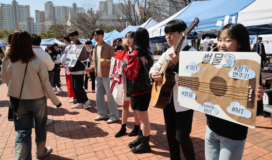 Pusan National University students hold up signs advertising university clubs to first-year students. [SONG BONG-GEUN]