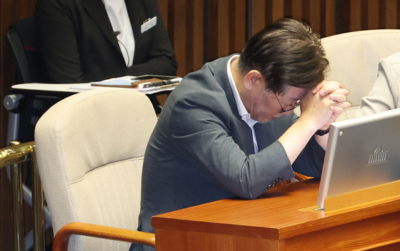 Democratic Party leader Lee Jae-myung sits with his head in his hands during a plenary session of the National Assembly in Seoul on Wednesday. [YONHAP]