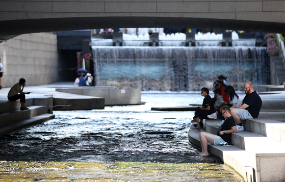 People sit in the shade along the Cheonggyecheon, a stream that flows through downtown Seoul, on Thursday as daytime temperatures remain between 26 and 31 degrees Celsius (78 and 88 degrees Fahrenheit). According to the weather agency, the daytime heat is expected to continue throughout the weekend. [NEWS1]