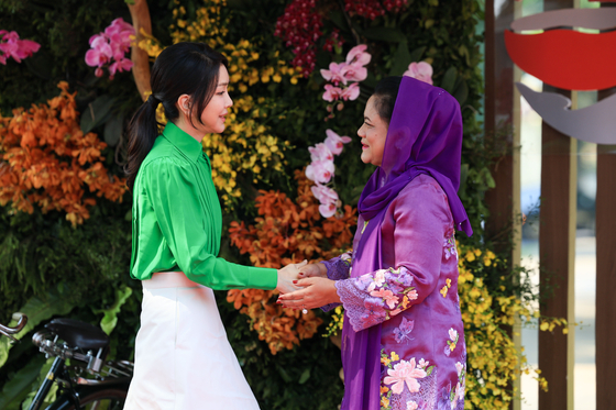 First lady Kim Keon Hee, left, greets Indonesian first lady Iriana Joko Widodo at Taman Mini Indonesia Indah park in Jakarta on Wednesday as they take part in a series of events arranged for the spouses of leaders attending the Asean summit this week. [JOINT PRESS CORPS]