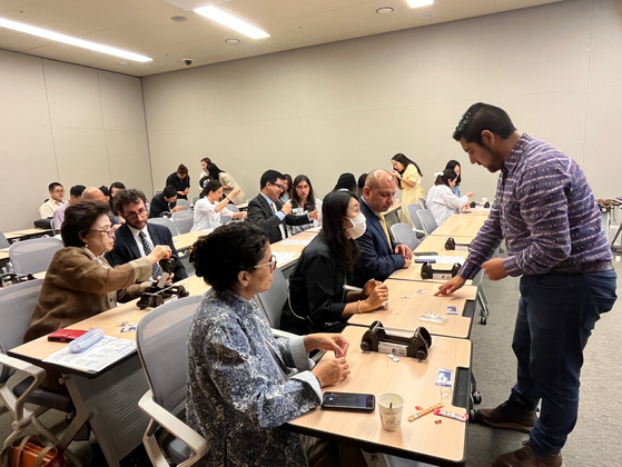 Mateo Perea Bernal, artist and founder of Tejidos Chakana, far right, explains during a beadwork workshop in Seoul on Thursday. Participants in the first row include Ambassador of Colombia to Korea Alejandro Pelaez Rodriguez, third from left. [ESTHER CHUNG]