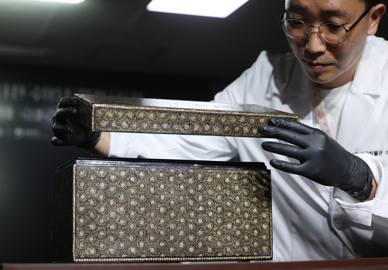 An official from the National Palace Museum of Korea carefully opens the lid of the returned najeon chilgi box that dates back to the Goryeo Dynasty (918-1392) on Wednesday at the museum in central Seoul. Najeon chilgi is lacquerware inlaid with mother-of-pearl. [YONHAP]