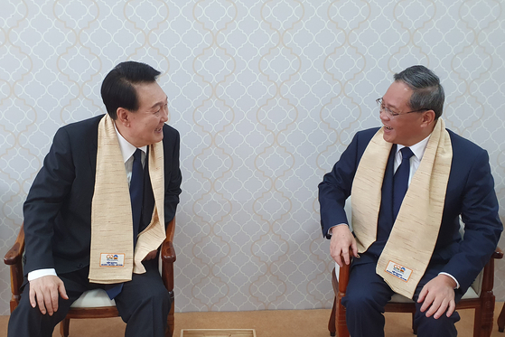 Korean President Yoon Suk Yeol, left, chats with Chinese Premier Li Qiang in the lounge at the Mahatma Gandhi memorial in New Delhi, India, on Sunday, following their bilateral meeting in Jakarta on Thursday. [JOINT PRESS CORPS]
