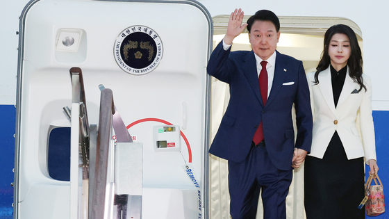  President Yoon Suk Yeol, left, waves alongside first lady Kim Keon Hee as they arrive on the presidential jet at Seoul Air Base in Gyeonggi on Monday morning after a weeklong visit to Indonesia and India for Asean and G20 events. [JOINT PRESS CORPS] 