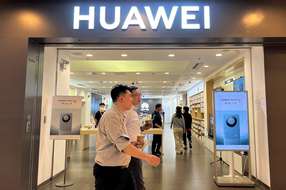People walk past a Huawei store with advertisements for the Mate 60 series smartphone, at a shopping mall in Beijing on Aug. 30. [REUTERS/YONHAP]
