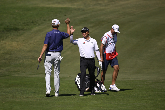 Kim Seong-hyeon celebrates with Patton Kizzire after holing out from the 14th fairway during the first round of the Fortinet Championship at Silverado Resort and Spa in Napa, California on Thursday.  [GETTY IMAGES]