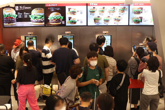 Customers place their orders at kiosks installed at a fast-food restaurant in Seoul. [YONHAP]