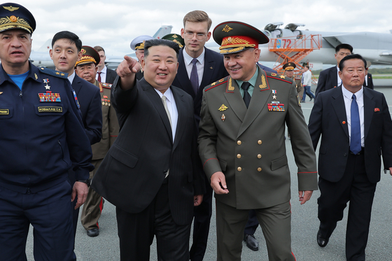 North Korean leader Kim Jong-un, left, speaks to Russian Defense Minister Sergei Shoigu, right, as they inspect Russian warplanes at the Vladivostok International airport in Vladivostok, in Russia’s Far East Saturday. [AP/YONHAP]