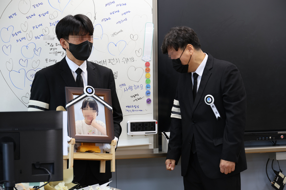 A family member carries a picture of an elementary school teacher who recently took her own life in the classroom where she taught in Daejeon. The teacher was reportedly harassed by students' parents relentlessly. [YONHAP]