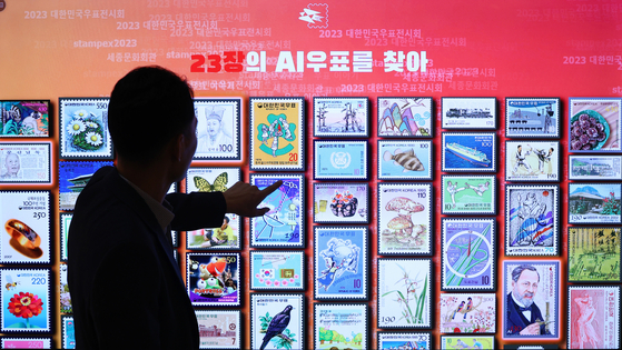 A staff member at the 2023 Korea Philatelic Exhibition demonstrates a postage stamp archive based on AI on a display screen at the Sejong Center for the Performing Arts in Jongno District, central Seoul, on Thursday. The stamp exhibition, which will run until Sept. 28, features various stamp collections, including a special edition stamp with boy band BTS. [YONHAP]