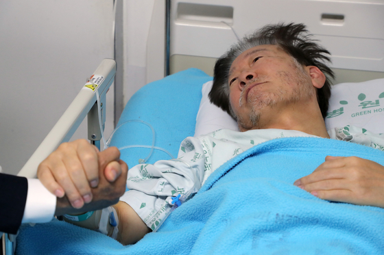 Democratic Party (DP) leader Lee Jae-myung holds the hand of DP floor leader Park Kwang-on at a hospital in Jungnang District, eastern Seoul, on Thursday morning. Lee has been on an intravenous drip since Monday, when he was admitted for treatment in the middle of his ongoing hunger strike. [YONHAP]